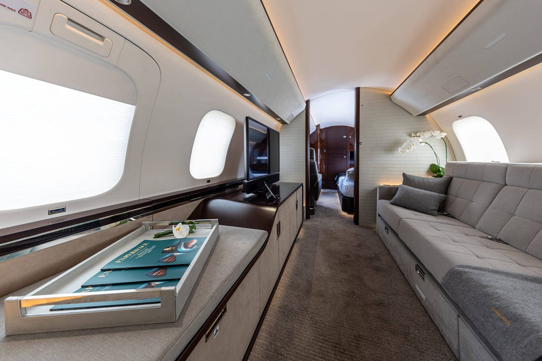 The main cabin of a Bombardier Global 7500, with a divan along one side and a bedroom beyond
